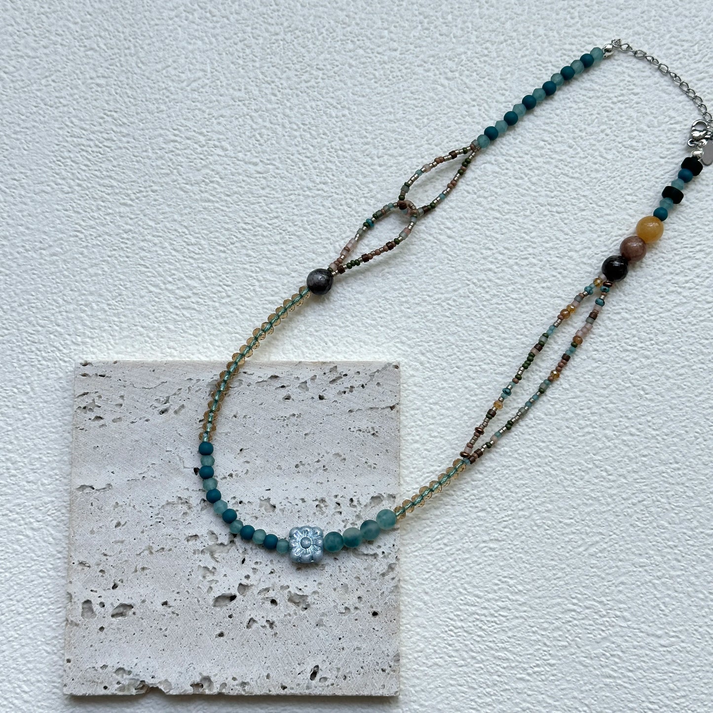 Full view of Aqua Loop Blossom Necklace hanging – handcrafted coastal palette of aqua and gold with asymmetrical loop detail