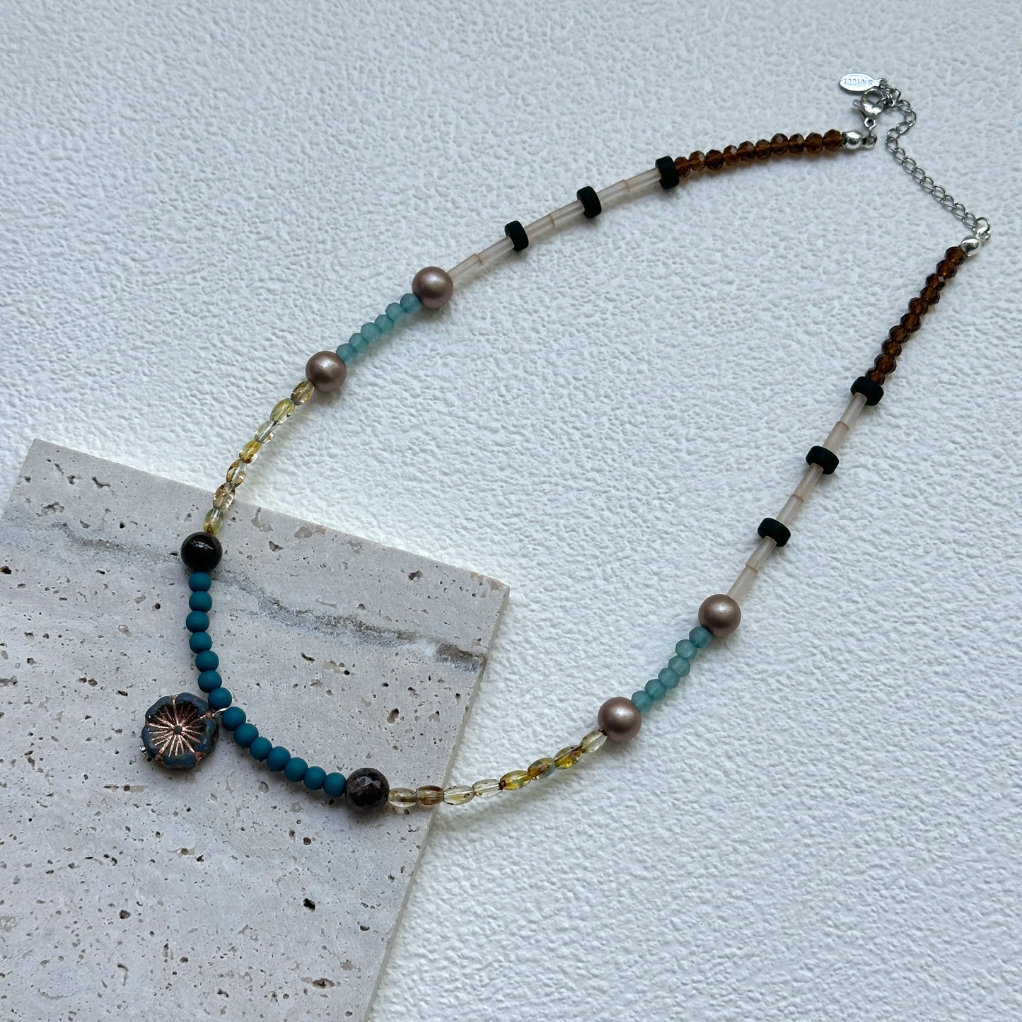 Lagoon Sunburst Necklace displayed on an oval tray – bright lagoon-blue beads and warm golden accents for a sunny seaside look