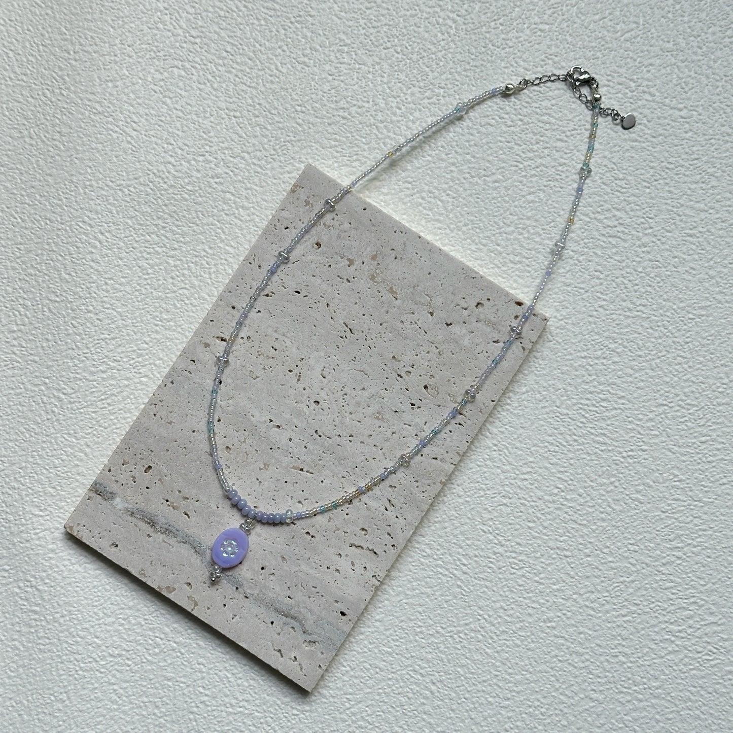Handmade Aurora Dew Necklace laid flat, showing iridescent beads and delicate pendant details