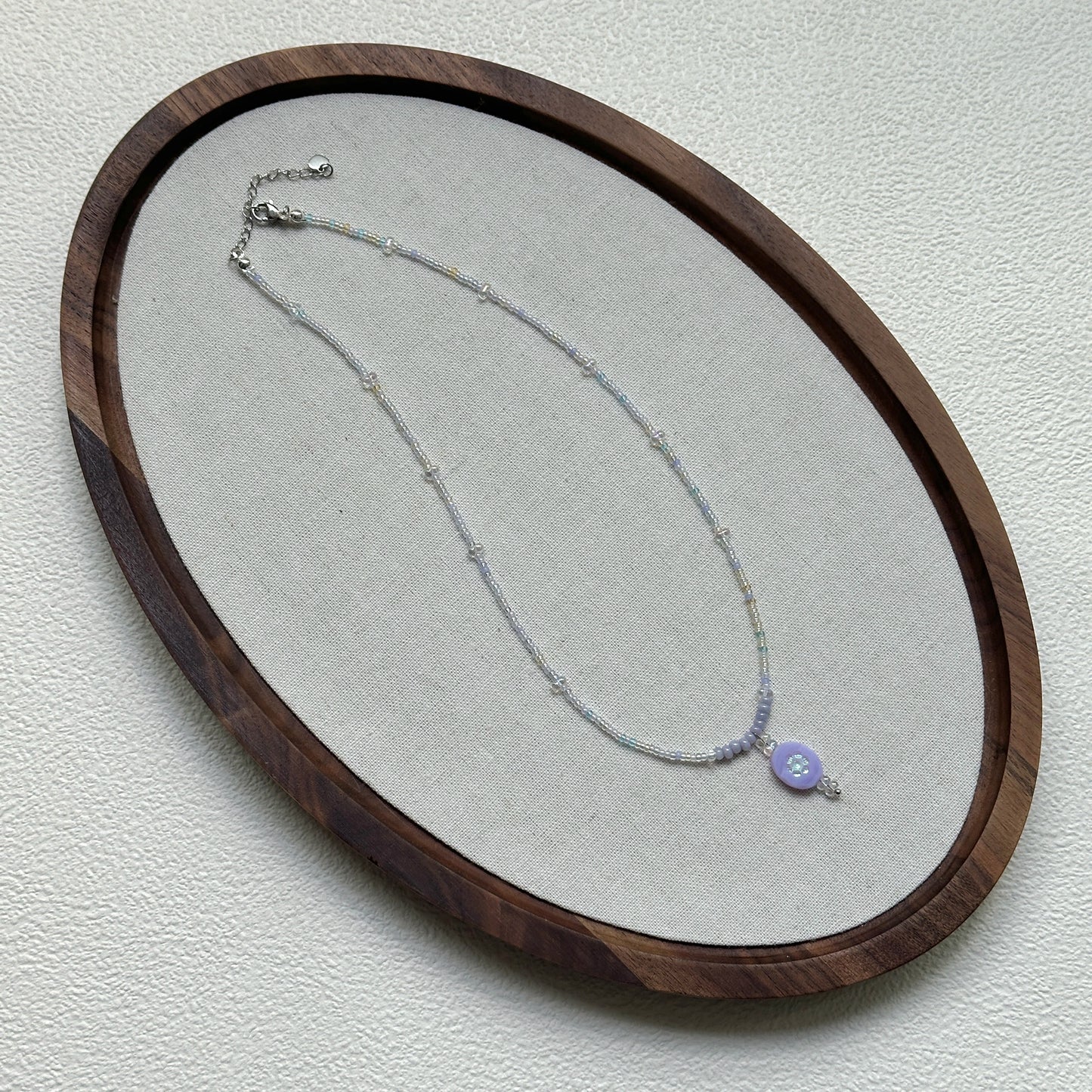Handmade Aurora Dew Necklace laid flat, showing iridescent beads and delicate pendant details2