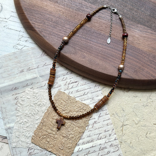 Amber Cross Necklace — flat lay on round wooden tray; amber-hued glass beads with freshwater pearl drop and cross pendant