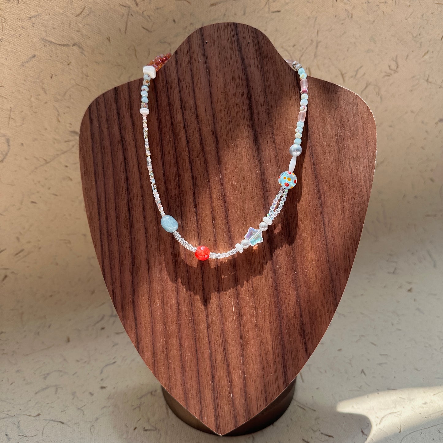 Candy Sky Necklace on wood display bust — pastel glass beads with red and blue accents, star charm