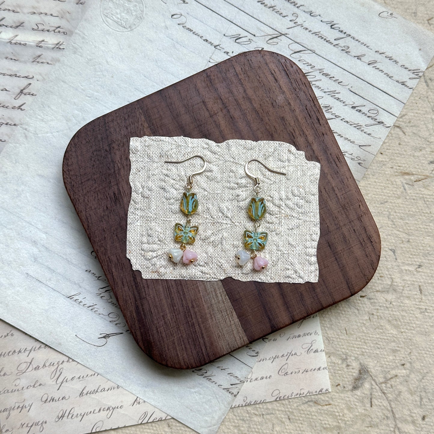 Butterfly Blossom Drops — close-up of tulip-cut glass, butterfly tiles, and blush/cream petal drops