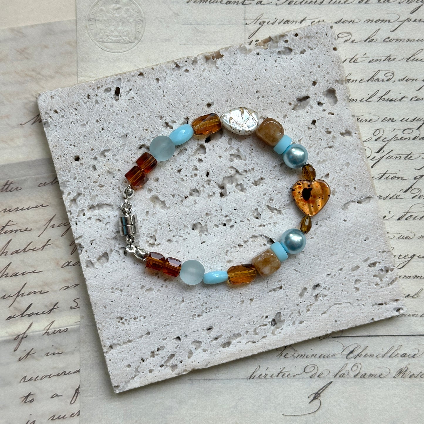Close-up of Amber Tide Bracelet showing heart-shaped amber bead accent and soft blue pearls.