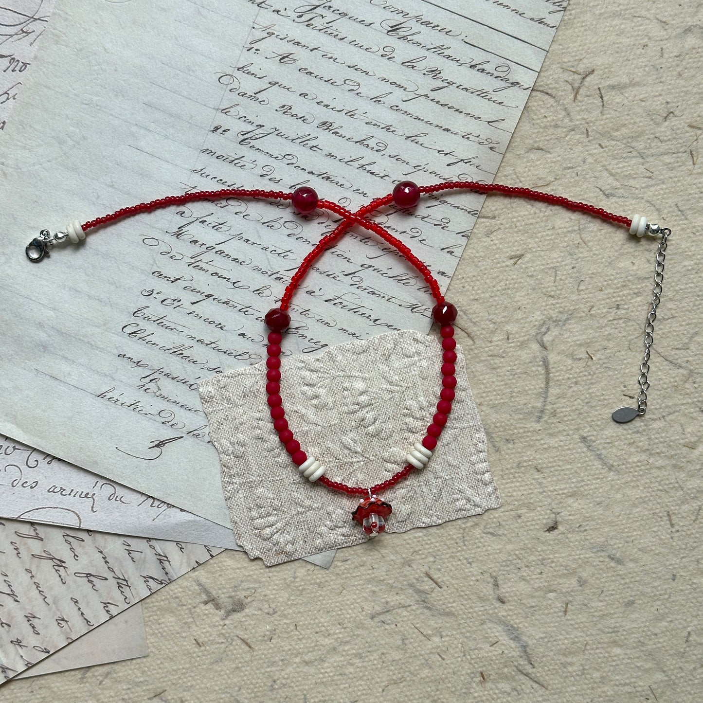Full view of Crimson Toadstool Necklace laid flat, combining red beads, ivory accents, and handcrafted mushroom pendant