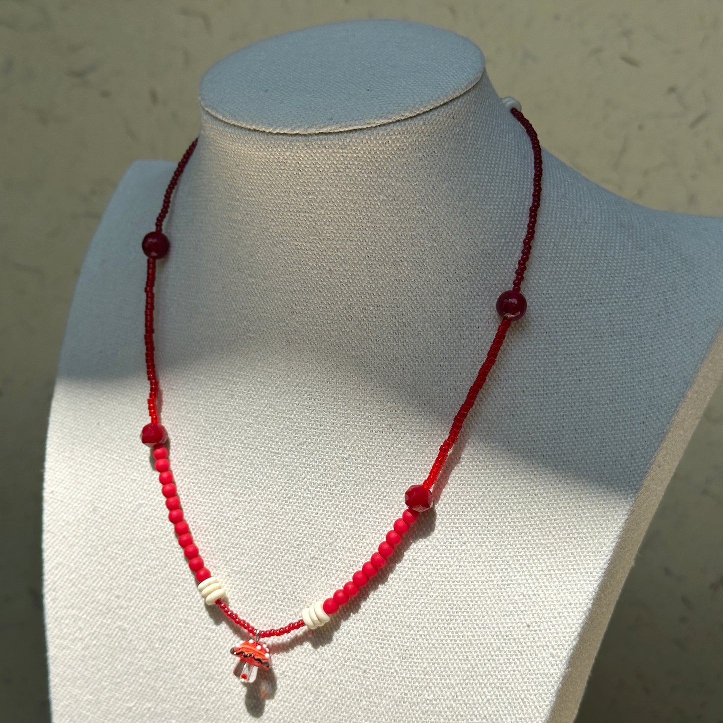 Crimson Toadstool Necklace worn on bust, highlighting crimson beads and playful lampwork mushroom charm