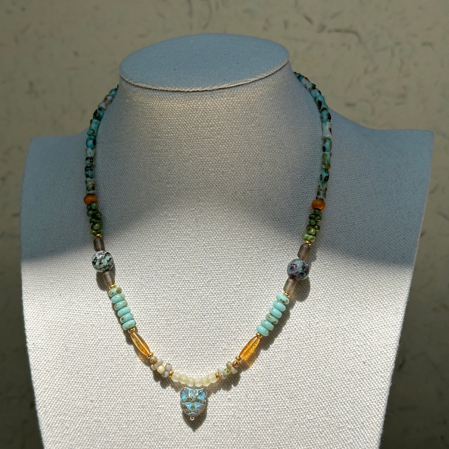 Verdant Owl Necklace worn on bust, highlighting owl pendant with harmonious mix of sage green, lagoon blue, ivory pearls, and golden accents