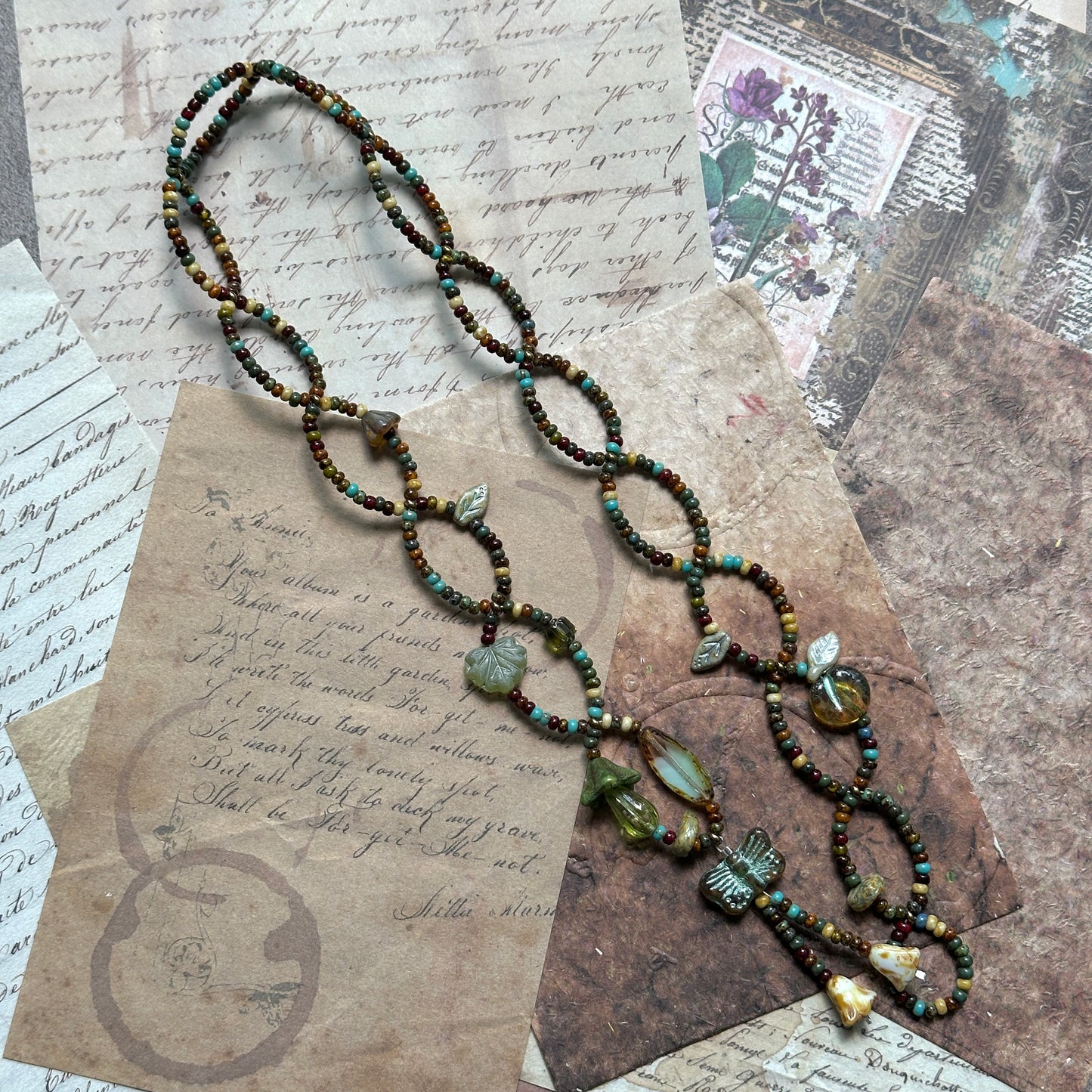 Close view of vine-link lariat showing olive, moss and amber Czech-glass beads and hearts; handcrafted, adjustable design.