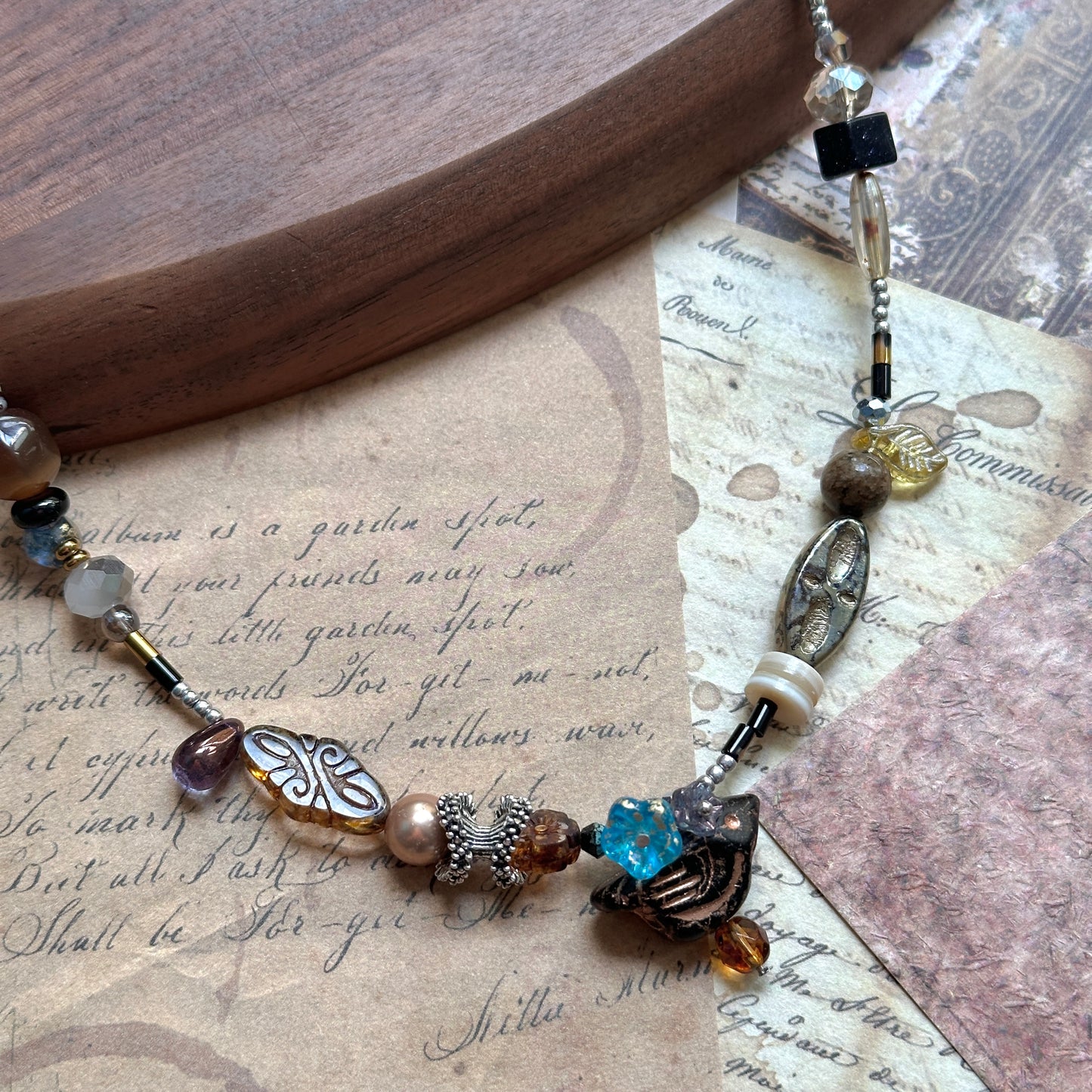 Close detail of Nomad Relic Necklace—carved leaf charm with bronze and onyx beads, Czech-glass accents, talisman look.