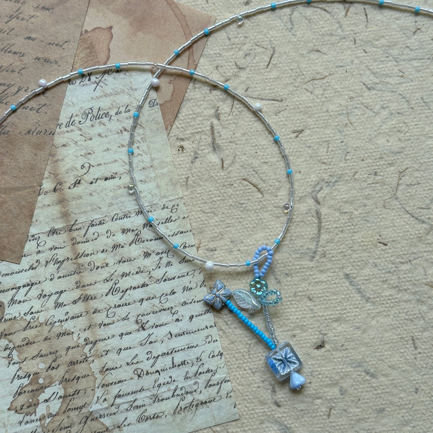 Close detail of Frosted Sky Necklace—icy blue beads, frosted glass flowers and crystal drop pendant; airy winter palette.