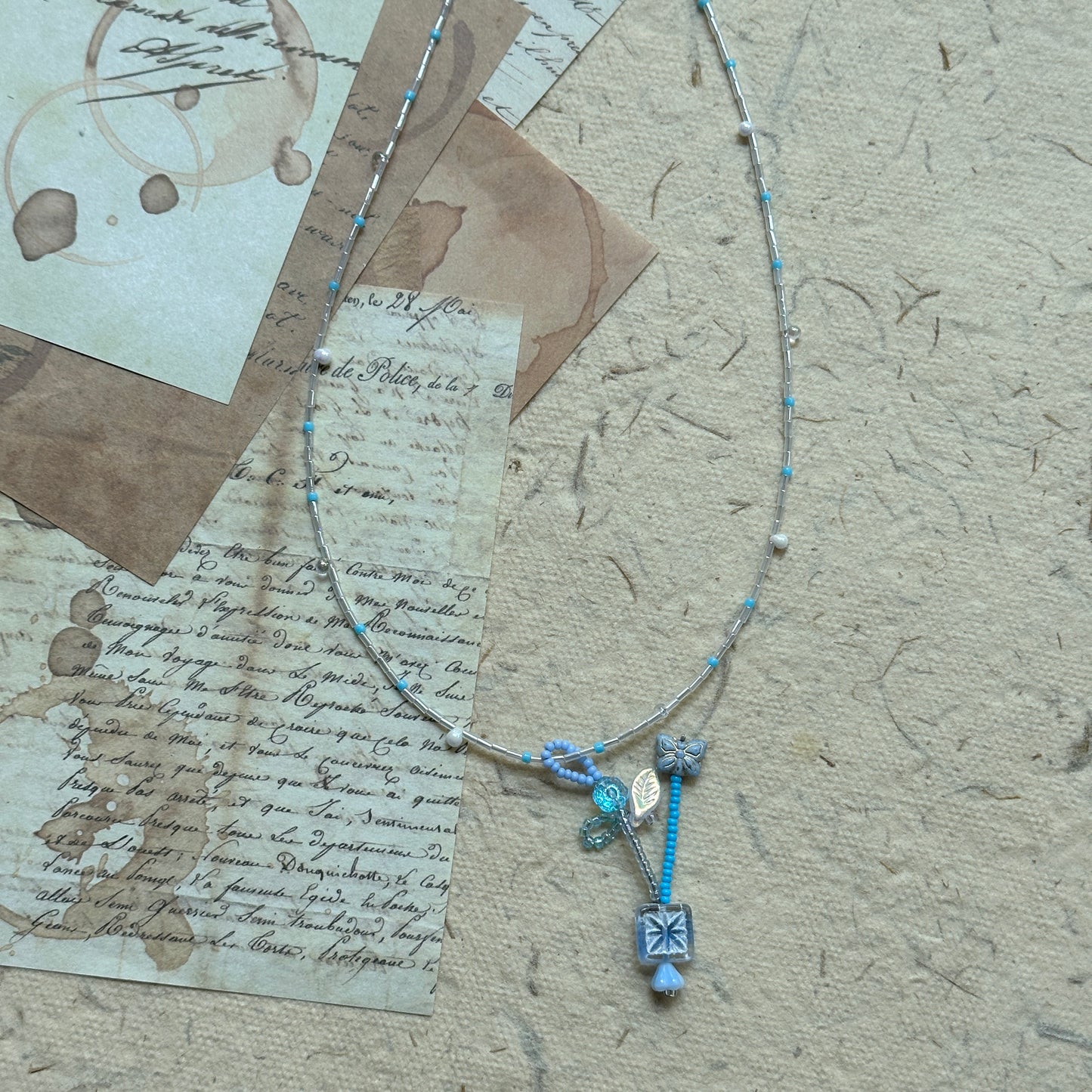 Angled flat lay highlighting crystal drops and frosted flower charms on the Frosted Sky Necklace; lightweight, luminous feel.