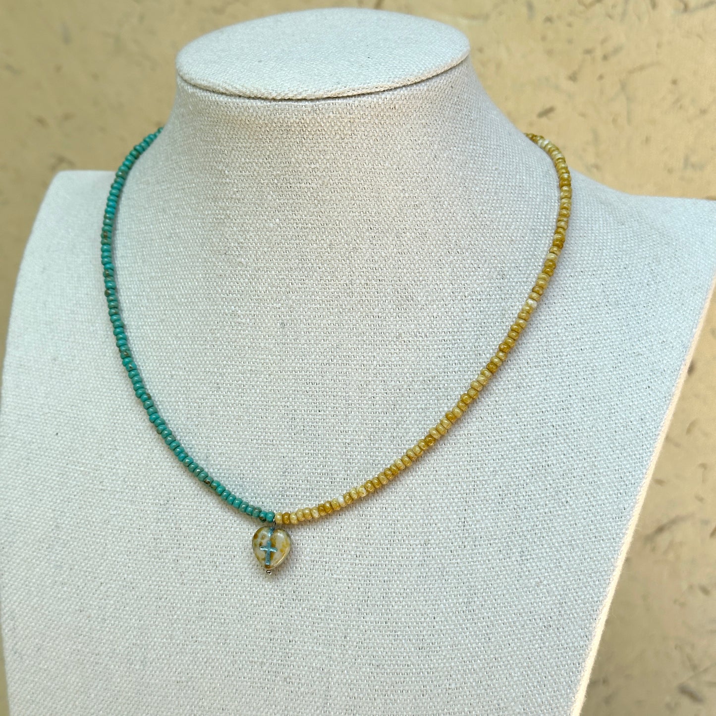 Faithlight Necklace on mannequin—slim two-tone beaded strand with a petite glass cross pendant; simple and easy to layer.