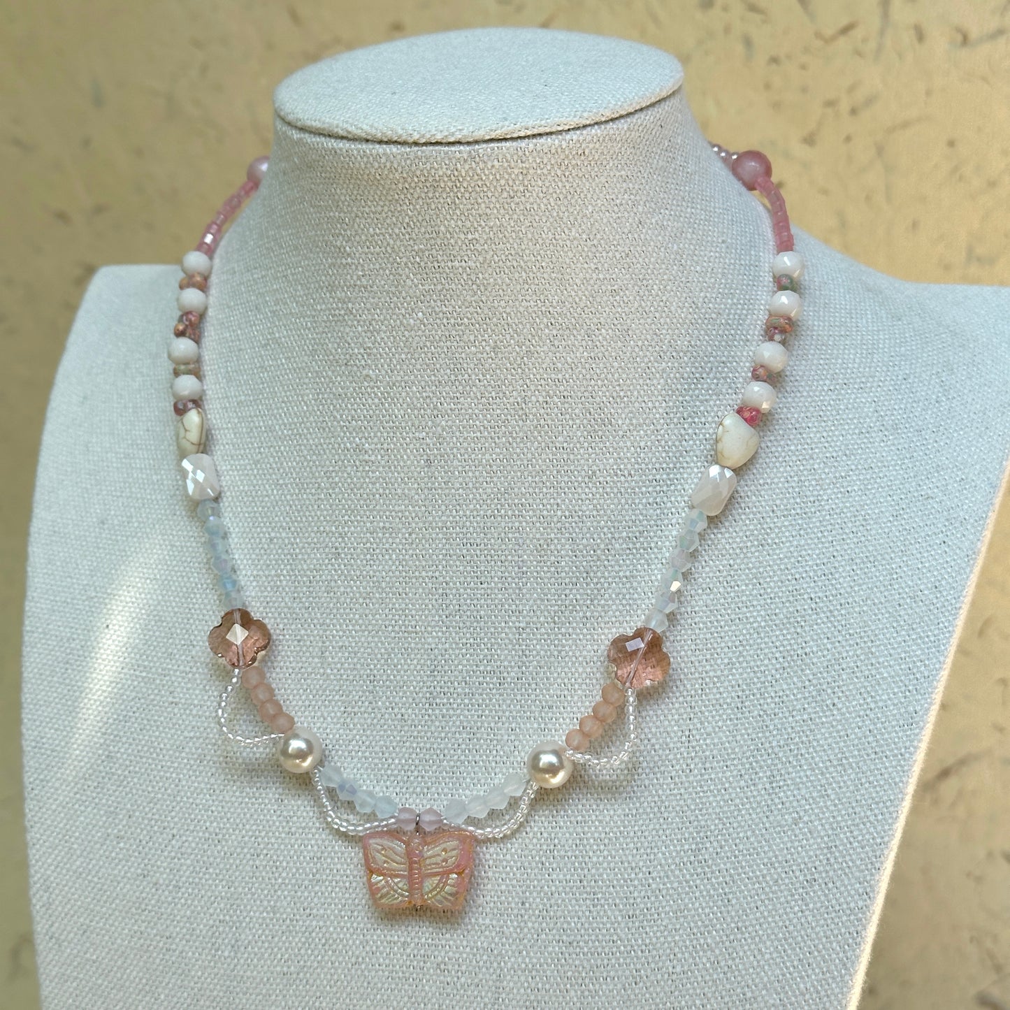 Blush Wing Necklace on mannequin—pressed-glass butterfly, pastel beads and pearl accents; lightweight, feminine and easy to wear.
