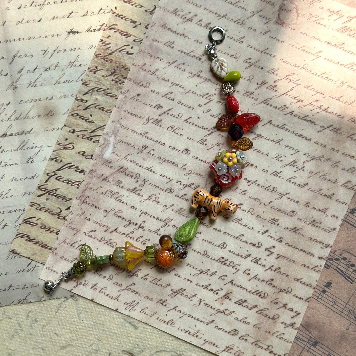Glazenya Tiger Orchard Bracelet featuring green leaf beads and red fruit charms, inspired by the colors of an autumn orchard