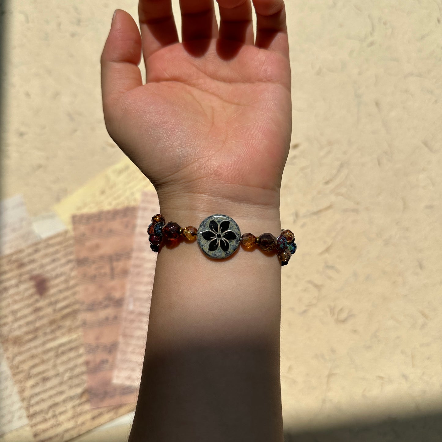 Antique Flower Window Bracelet worn on wrist, warm amber and garnet tones with bronze accents, refined handcrafted silhouette