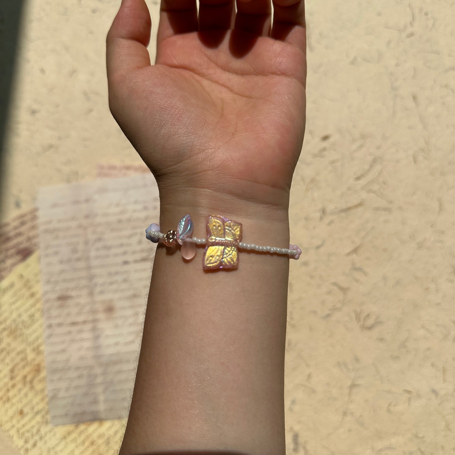 Blush Butterfly Dream Bracelet worn on wrist, pink butterfly and floral beads shimmering softly with gold accents, feminine spring style