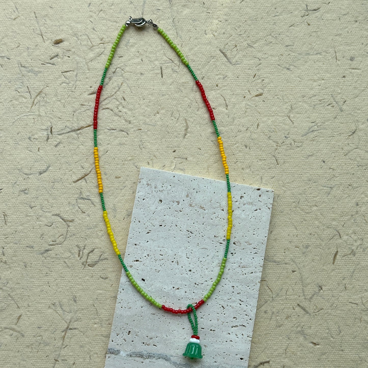 Close-up of green jelly-cake style pendant with red accent loop