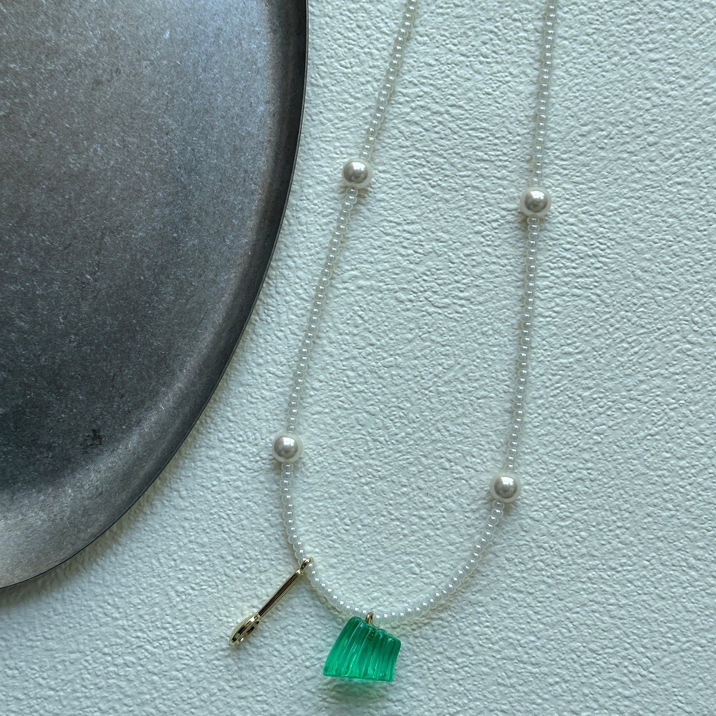 Close-up of transparent green glass pendant with seed beads