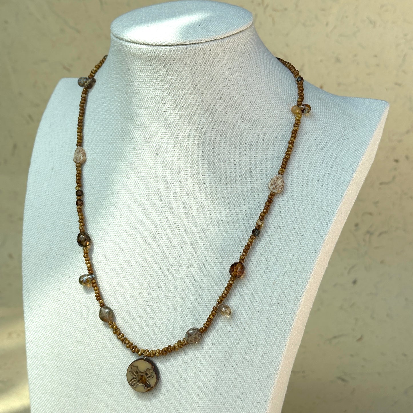 Rustic brown seed bead strand with zodiac-inspired design