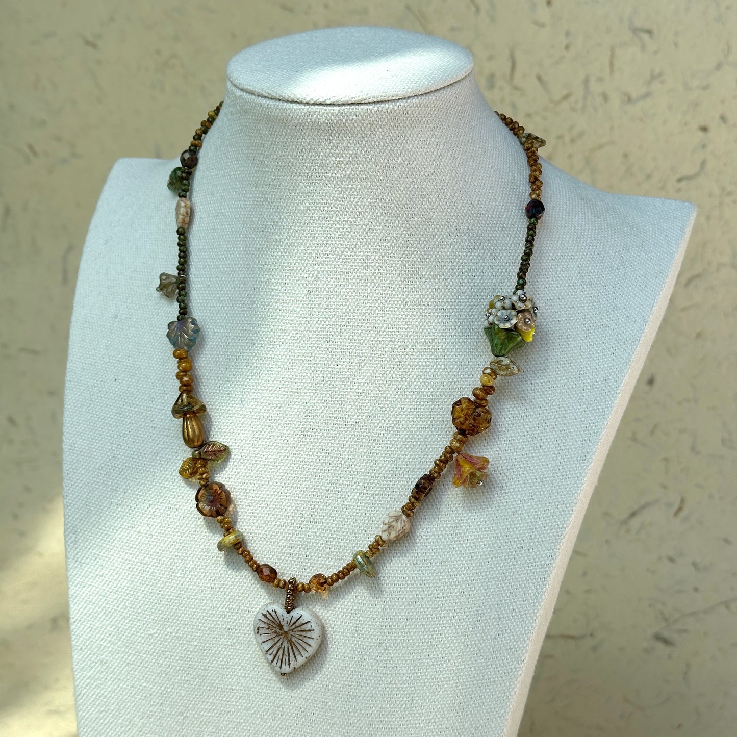 Full view of Heart of Leaves Necklace styled with vintage paper props