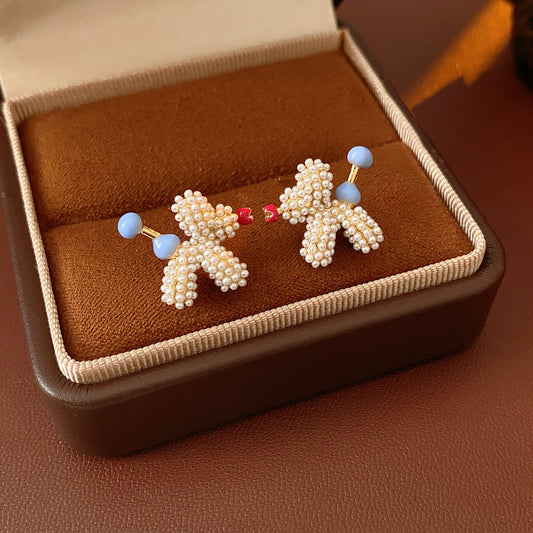Balloon dog stud earrings crafted from imitation pearls with blue bead details — Playful Poodle Pearl Studs.