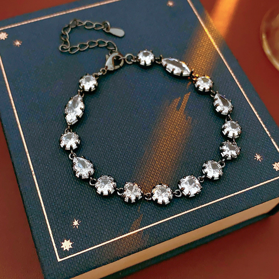 Midnight Sparkle Bracelet with round and pear-cut zircons set in noir metal, adjustable chain