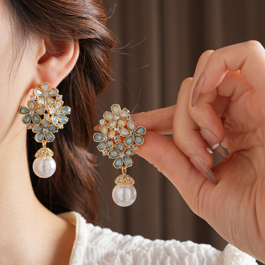 Gold floral cluster earrings with ice-blue petals, crystal accents, and a single luminous faux-pearl drop — Ethereal Petal Pearl Earrings.