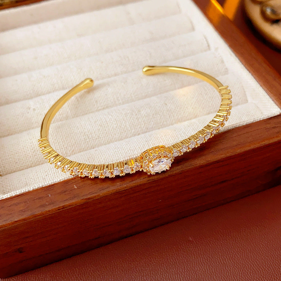 Elegant open bangle in gold with sparkling zircon stones and a marquise centerpiece, light-luxury adjustable bracelet.