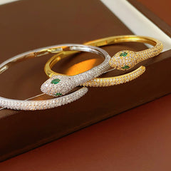 Gold and silver snake-shaped zircon bangles with emerald eyes — Serpent Luxe Bangle by Glazenya.