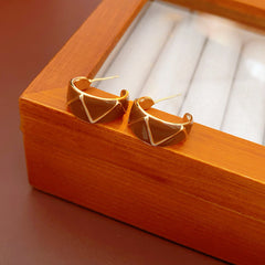 Set of four geometric enamel hoop earrings in white, blue, coffee, and green displayed in a jewelry tray