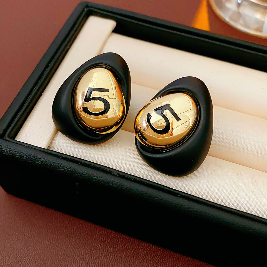 Matte pebble stud earrings with mirrored gold dome engraved with 5 — in white, black, coffee, and red — Gilded Numeral 5 Pebble Studs.