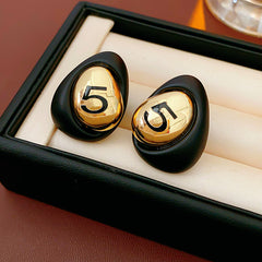 Matte pebble stud earrings with mirrored gold dome engraved with 5 — in white, black, coffee, and red — Gilded Numeral 5 Pebble Studs.