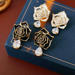 Gold-tone rose stud earrings with ivory and black enamel petals plus teardrop zircon dangles — Gilded Rose Teardrop Studs.