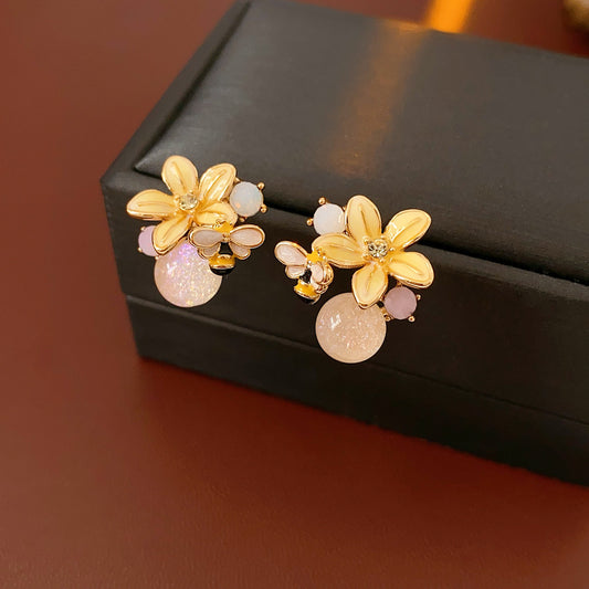 Honeybee Blossom Crystal Stud Earrings — gold flower studs with tiny bee charm and pink crystal orb on black jewelry box