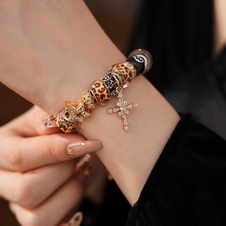 Leopard Cross Luxe Bracelet with leopard-patterned beads, zircon accents, black 8-ball bead, and cross pendant on gold chain