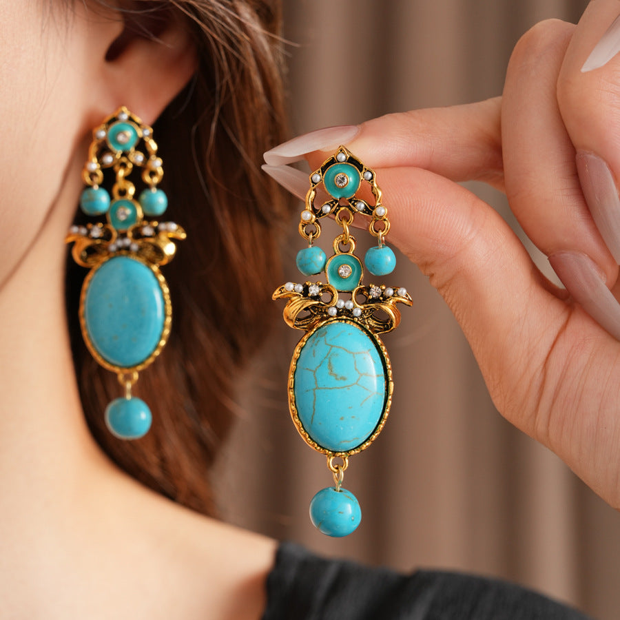 Gold filigree earrings with large turquoise cabochons, crystal accents, and dangling bead — Azure Oasis Turquoise Earrings.