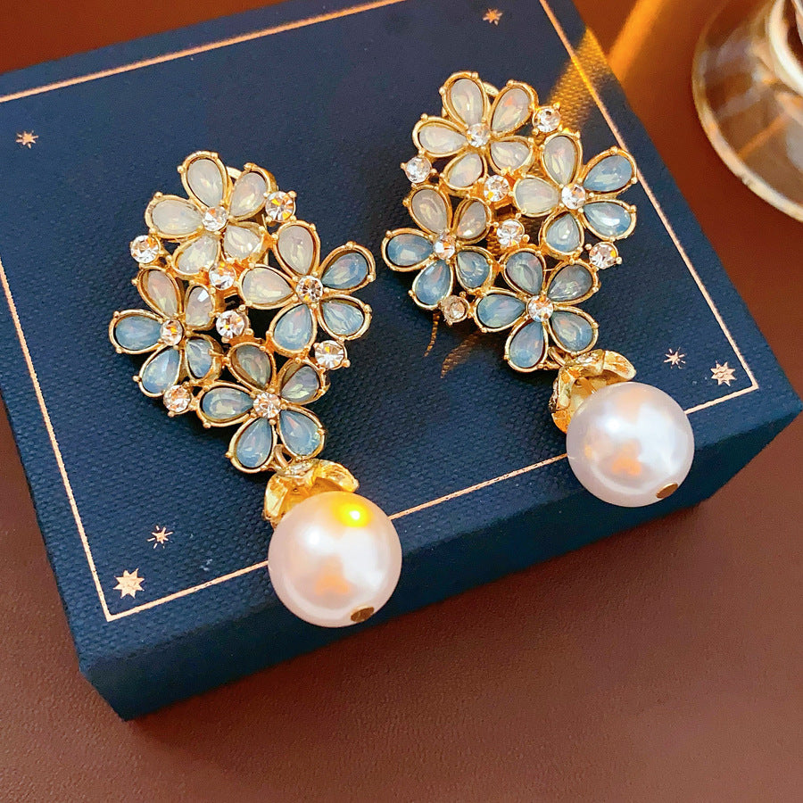 Gold floral cluster earrings with ice-blue petals, crystal accents, and a single luminous faux-pearl drop — Ethereal Petal Pearl Earrings.