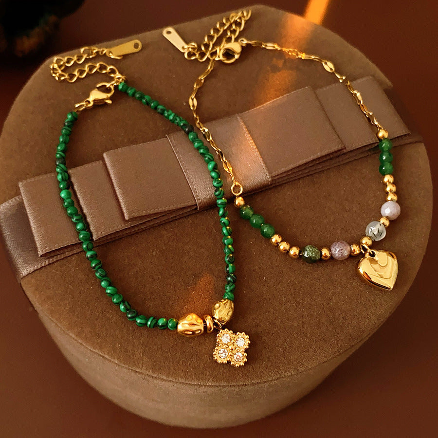 Two variant options of a malachite charm bracelet: beaded green strand with a crystal bloom charm, and a gold-tone chain with malachite accents and a heart pendant — Malachite Charm Bracelet (Variants).