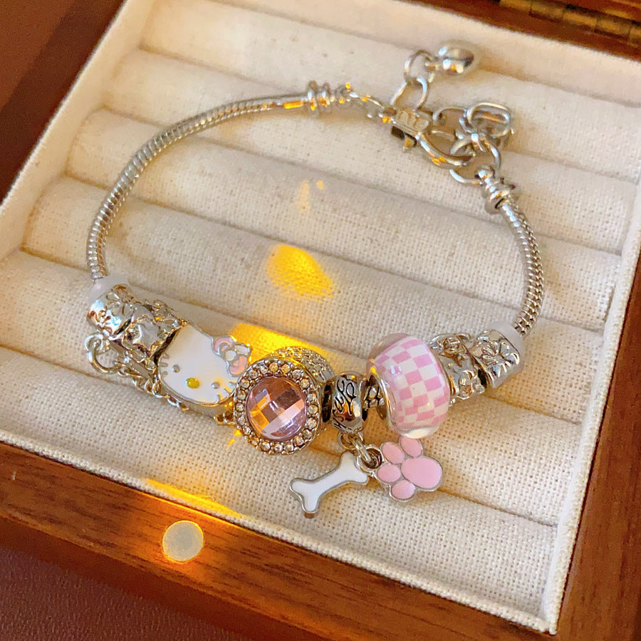 Rosy Pawprints Charm Bracelet — silver-tone snake chain with pink crystal bezel, checker enamel bead, cat-with-bow, paw and bone charms in jewelry tray