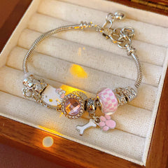 Rosy Pawprints Charm Bracelet — silver-tone snake chain with pink crystal bezel, checker enamel bead, cat-with-bow, paw and bone charms in jewelry tray