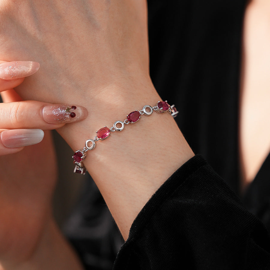 Oval Radiance Zircon Bracelet with silver-tone links and rose zircon stones, displayed on a book background
