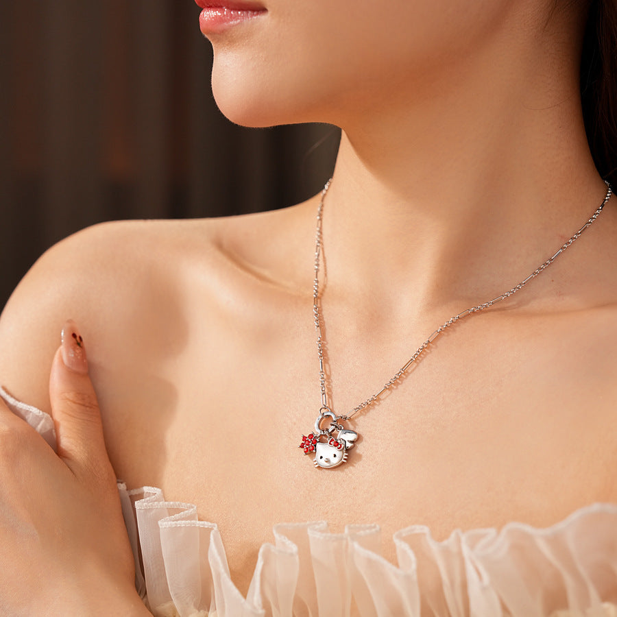 Silver-tone necklace with a cute cat face charm, red bow, red flower and clover accents; copper base with zircon details; 52 cm chain, 1.6 cm pendant, displayed on a black jewelry pad.