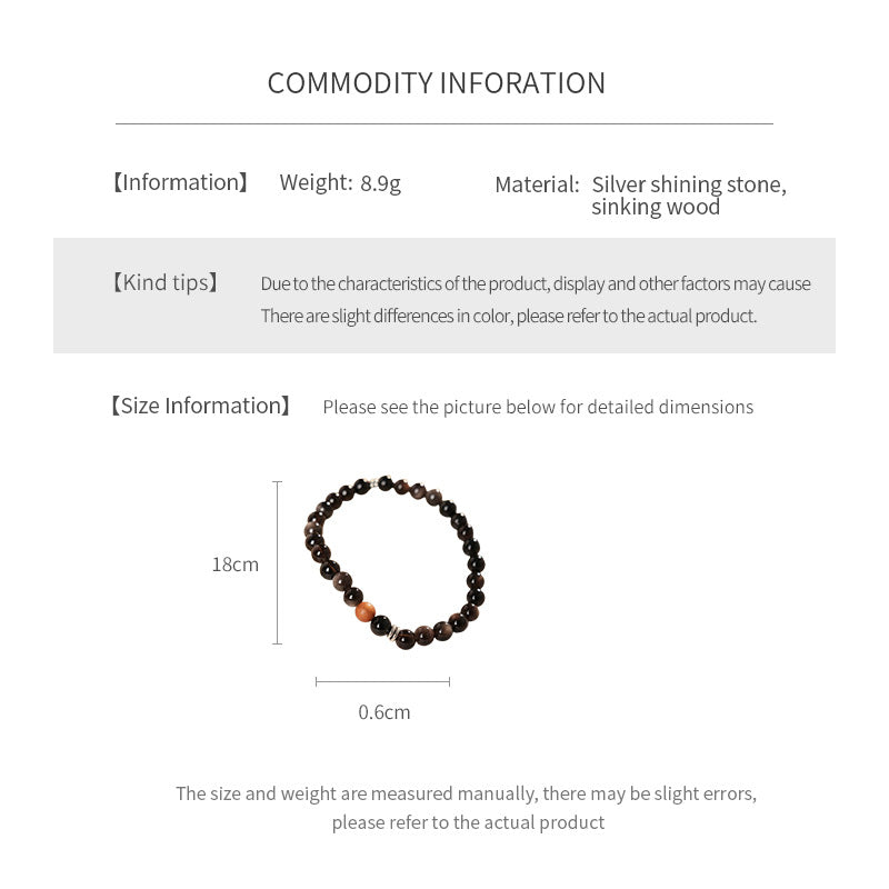 Sleek black silver-sheen stone beaded bracelet with one warm wood bead and silver ring spacers on a ceramic dish — Shadowwood Sheen Bracelet.