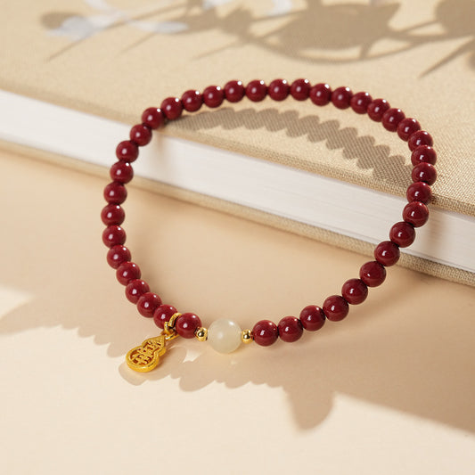 Red cinnabar beaded bracelet with Hetian jade bead and a gold-tone gourd charm.