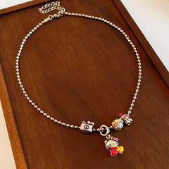 City Voyager Cat Charm Necklace — silver-tone ball chain with enamel cat and camera charms, travel-inspired charm cluster on black pouch