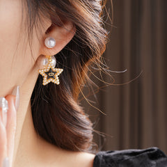 Double-pearl stud earrings with gold-tone butterfly and star charms displayed in a jewelry tray — Double Pearl Charm Studs.