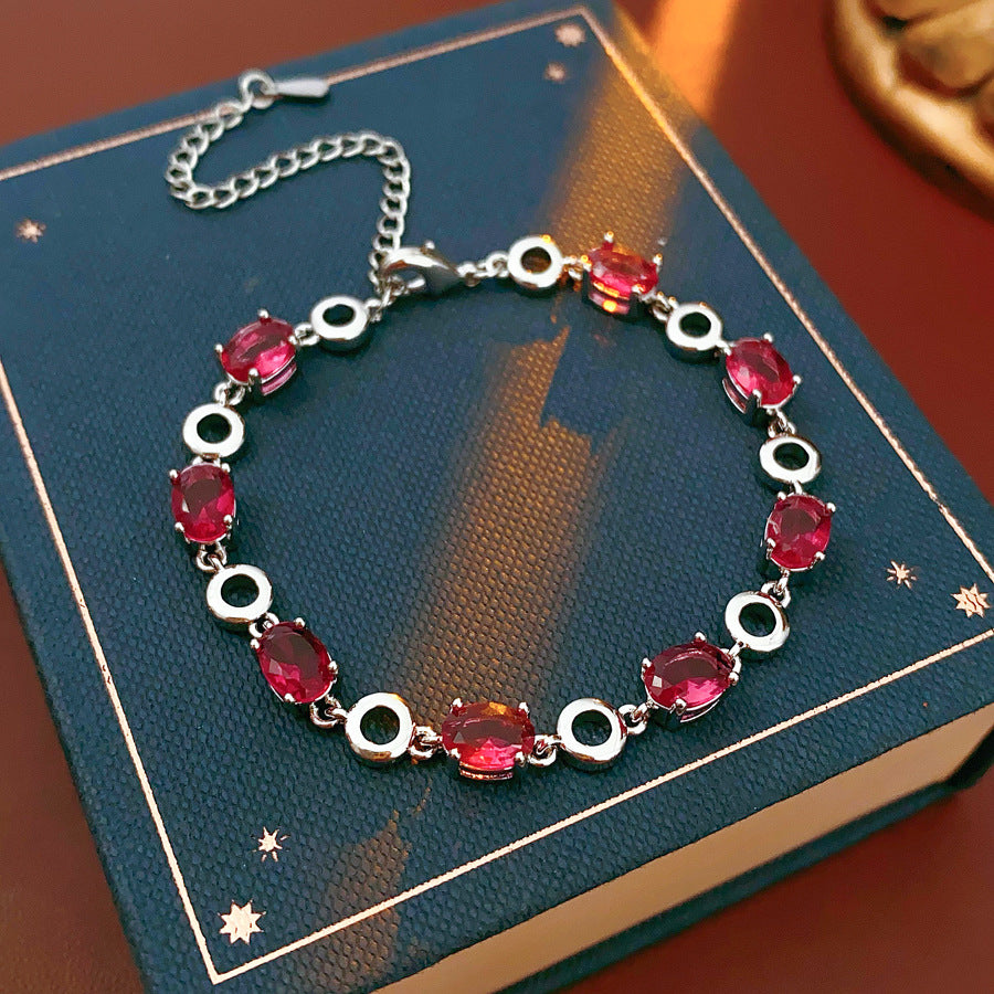 Oval Radiance Zircon Bracelet with silver-tone links and rose zircon stones, displayed on a book background