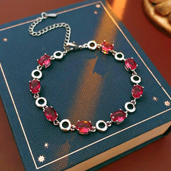 Oval Radiance Zircon Bracelet with silver-tone links and rose zircon stones, displayed on a book background