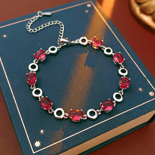 Oval Radiance Zircon Bracelet with silver-tone links and rose zircon stones, displayed on a book background