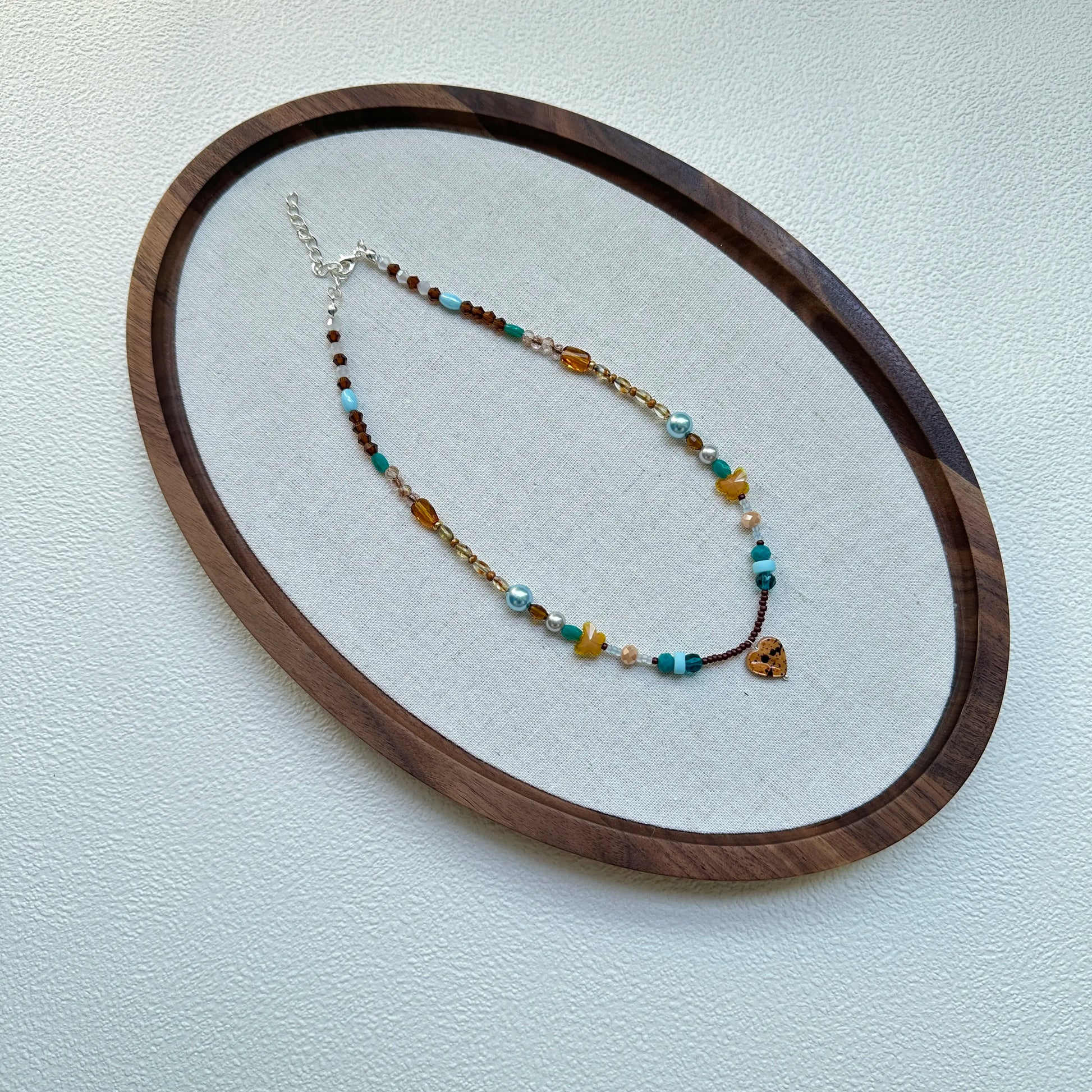 Close-up of amber heart glass pendant with ocean-turquoise bead